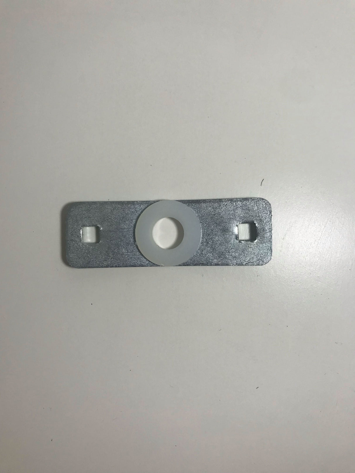 Metal bracket with circular hole on a grey background