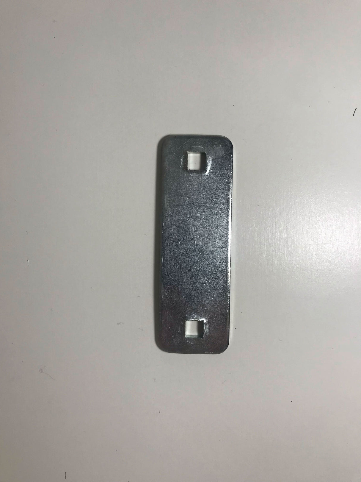 Metallic rectangular object on a light grey background