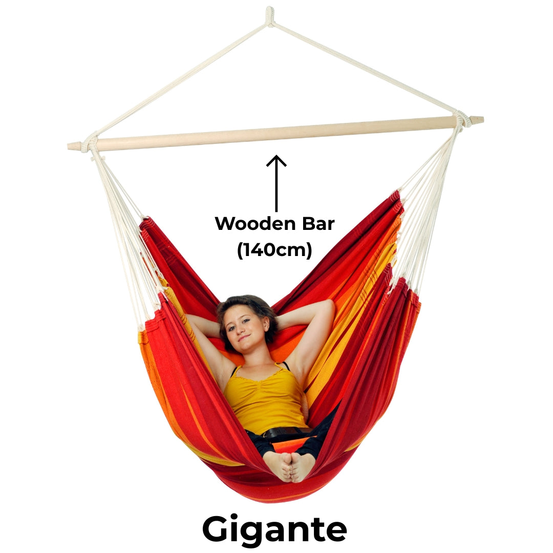 Red and yellow hammock with wooden bar labeled, featuring a person relaxing inside.