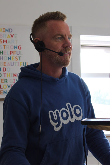 A man with a blue jumper with a headset on