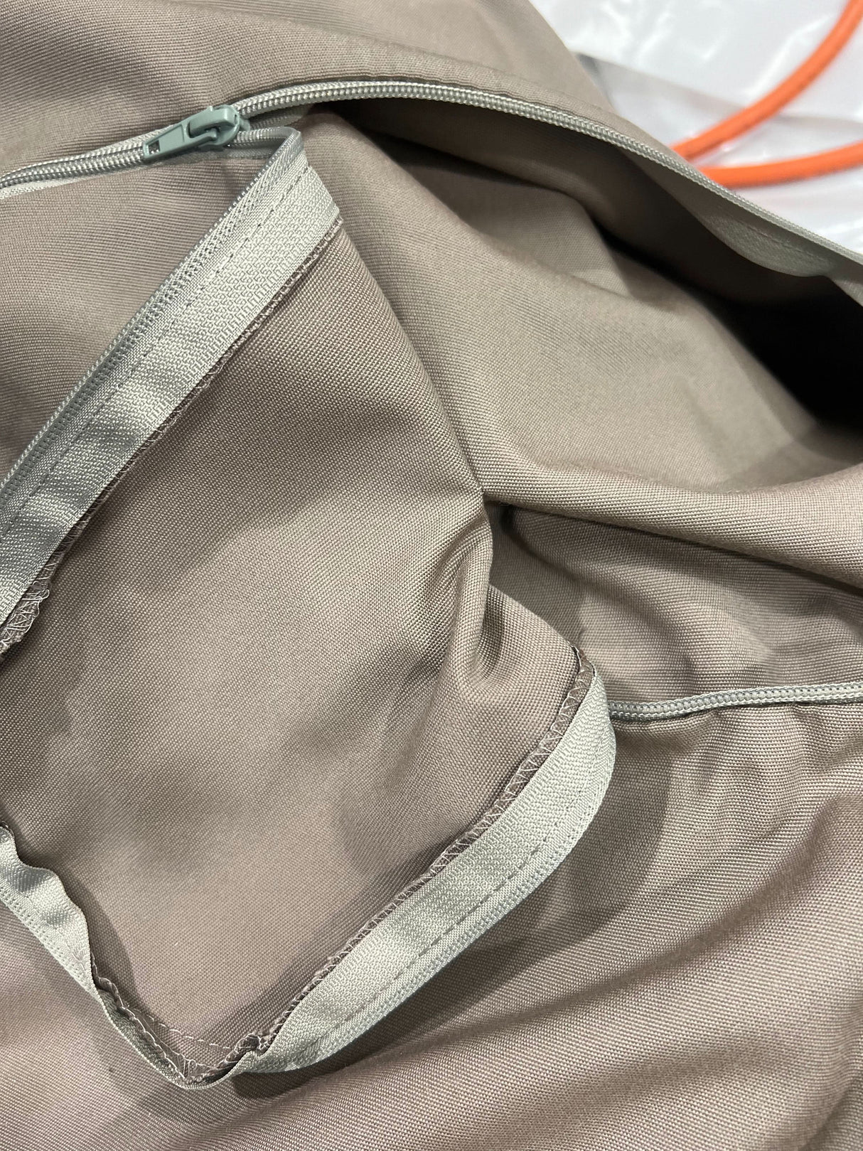 Close-up of a beige jacket with a zipper and mesh lining.