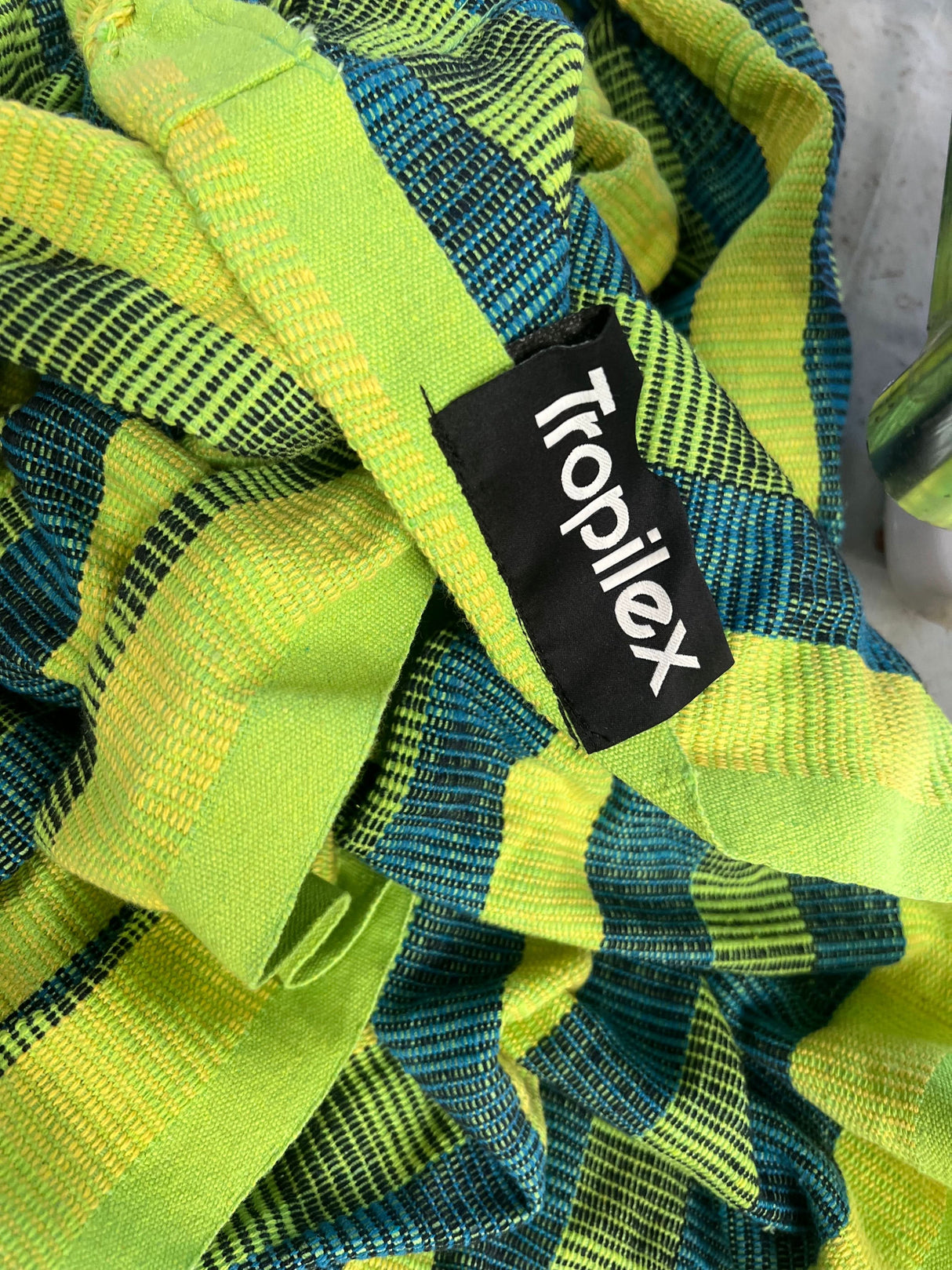 Close-up of a green and blue textured fabric with a Tropilex label.