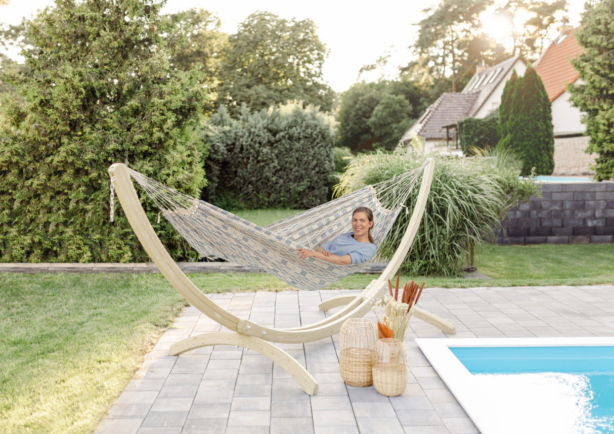 Person relaxing in a hammock by a pool in a garden setting