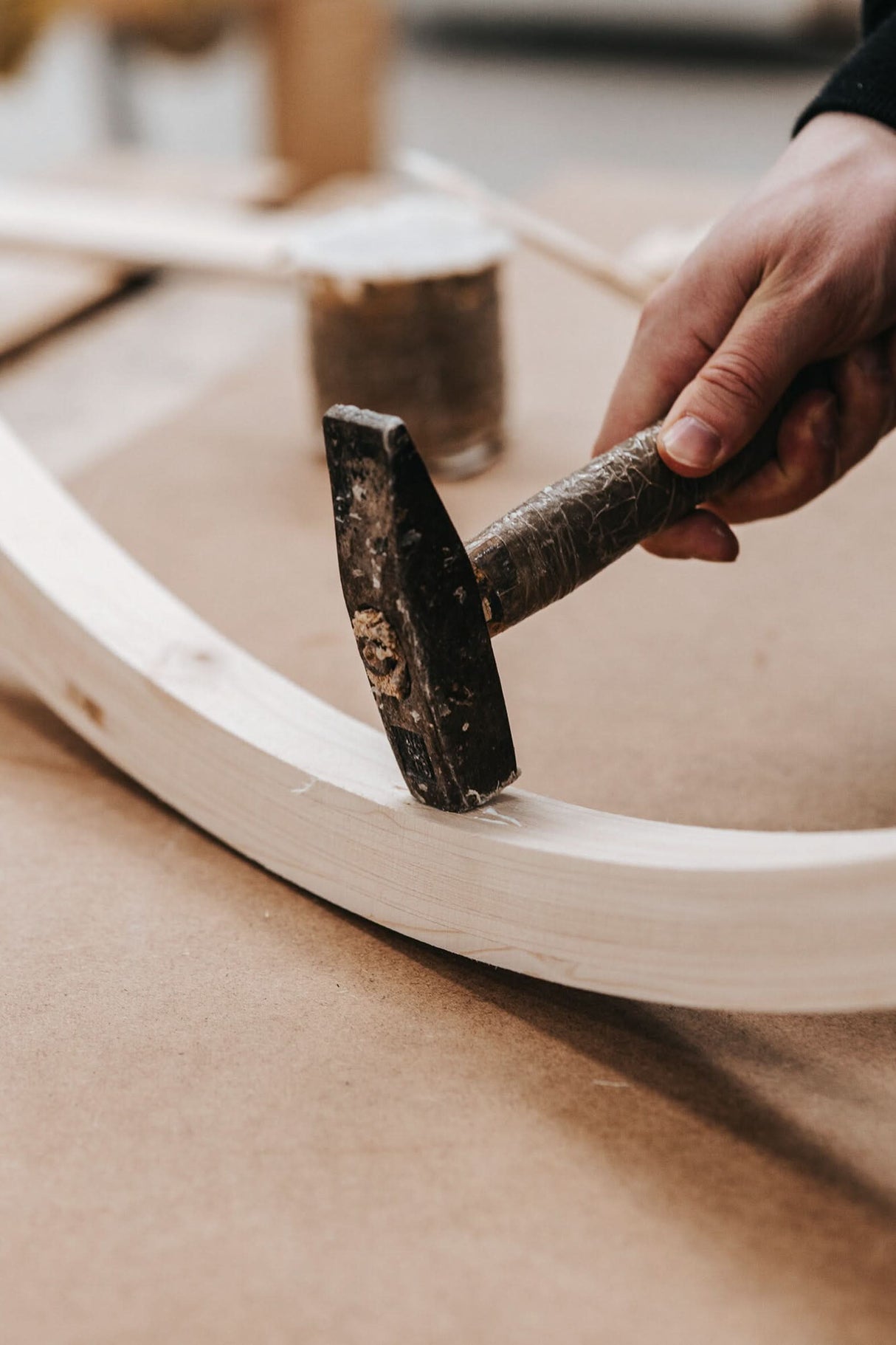Hand using a hammer on a wooden chair rim