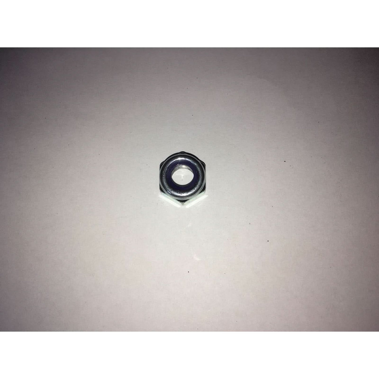 Metal hex nut on a light grey background