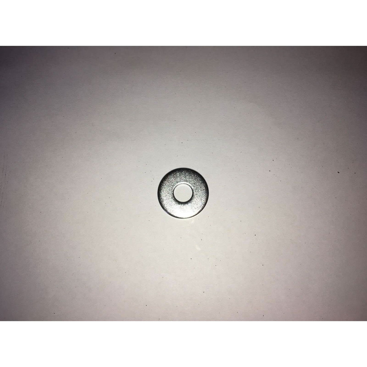 Close-up of a metallic drain cover on a light grey background