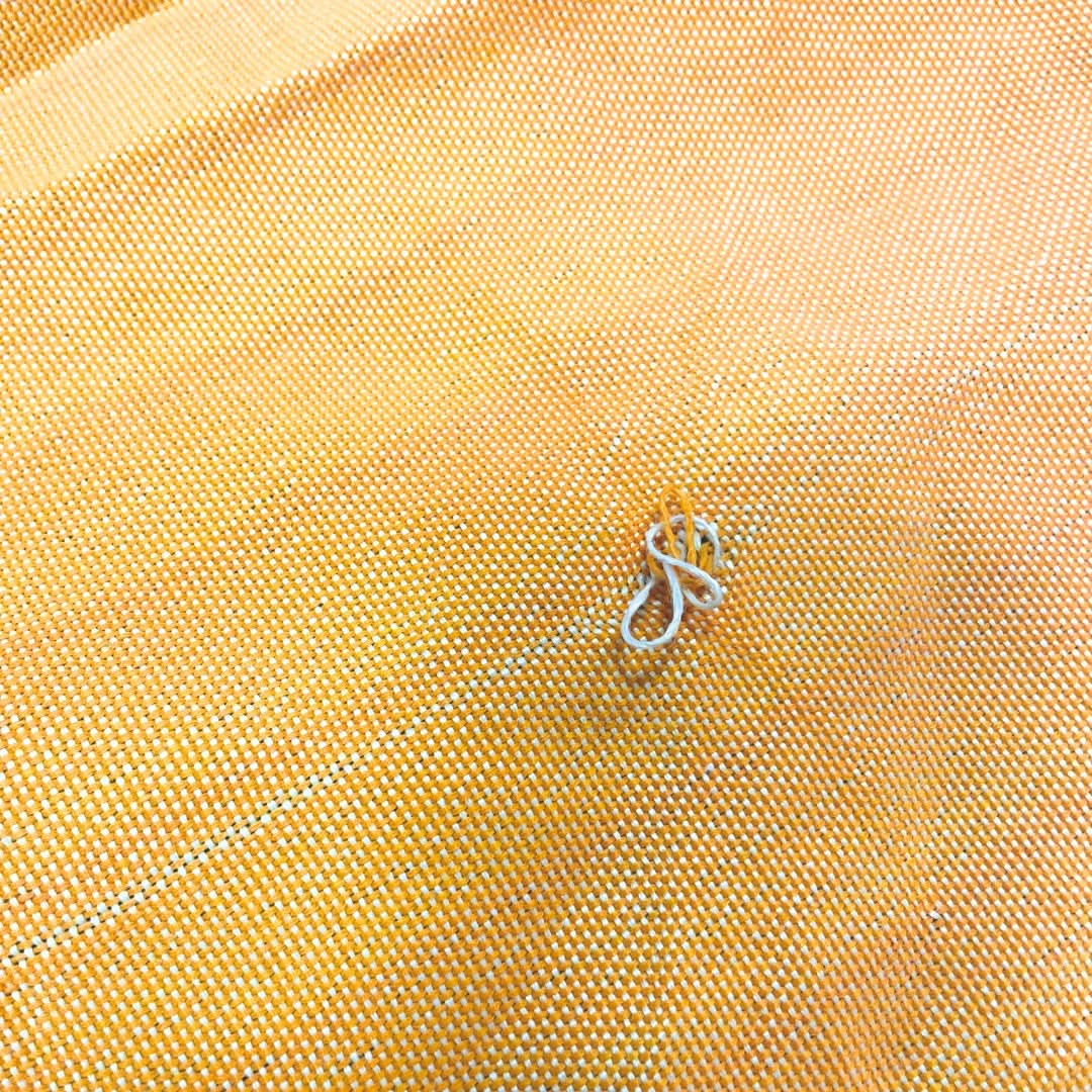 Close-up of yellow fabric with a small metal object on it