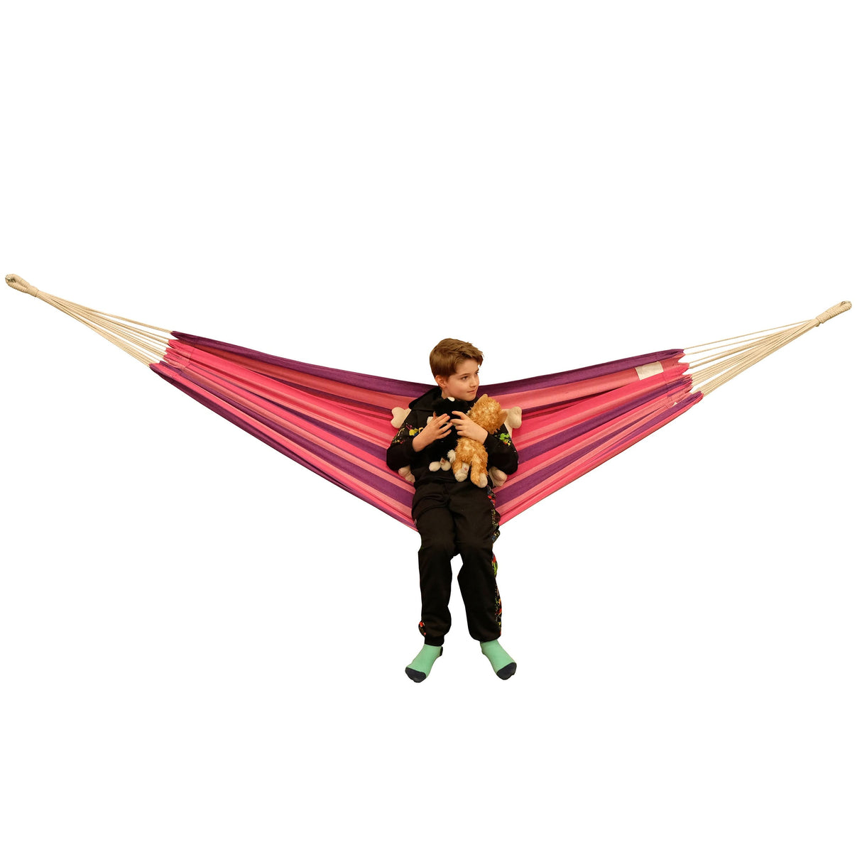 Child holding a teddy bear in a red and pink hammock on a white background