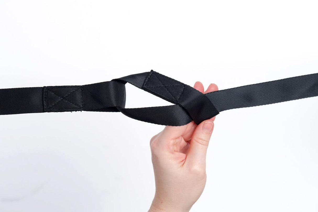 Hand holding a black belt against a white background