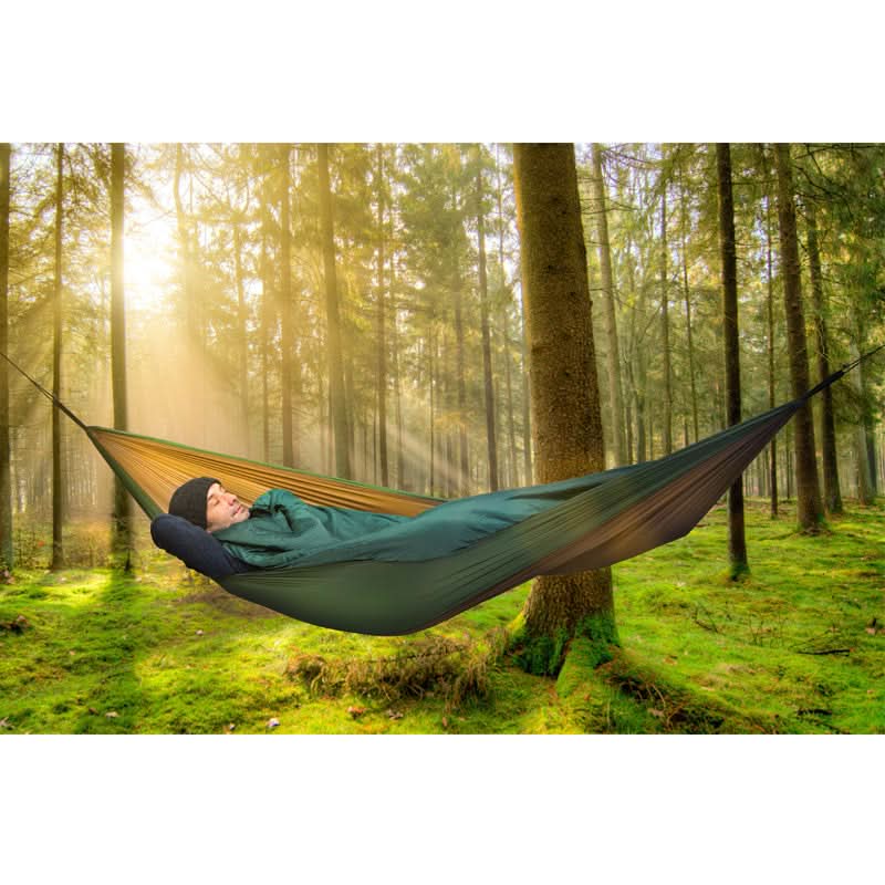 Person relaxing in a hammock in a forest with sunlight filtering through the trees.
