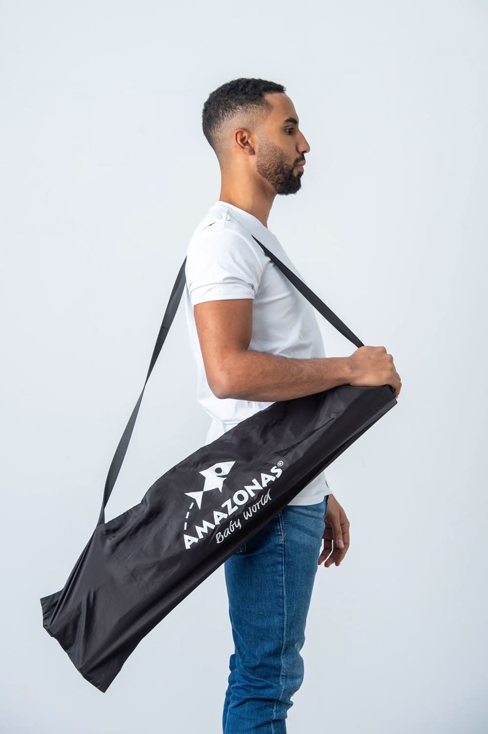 Man holding a black Amazonas yoga mat bag against a white background