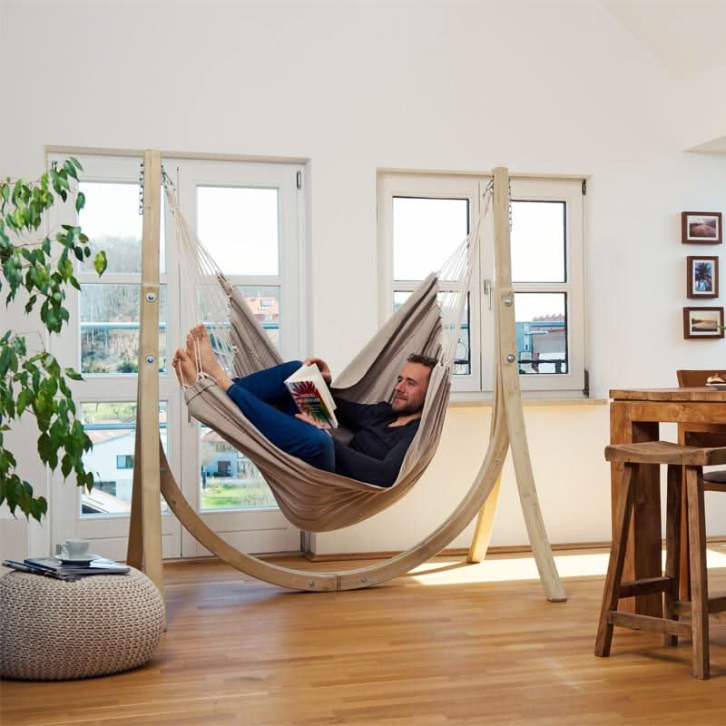 A man reading a book in a hammock chair in a modern living room.