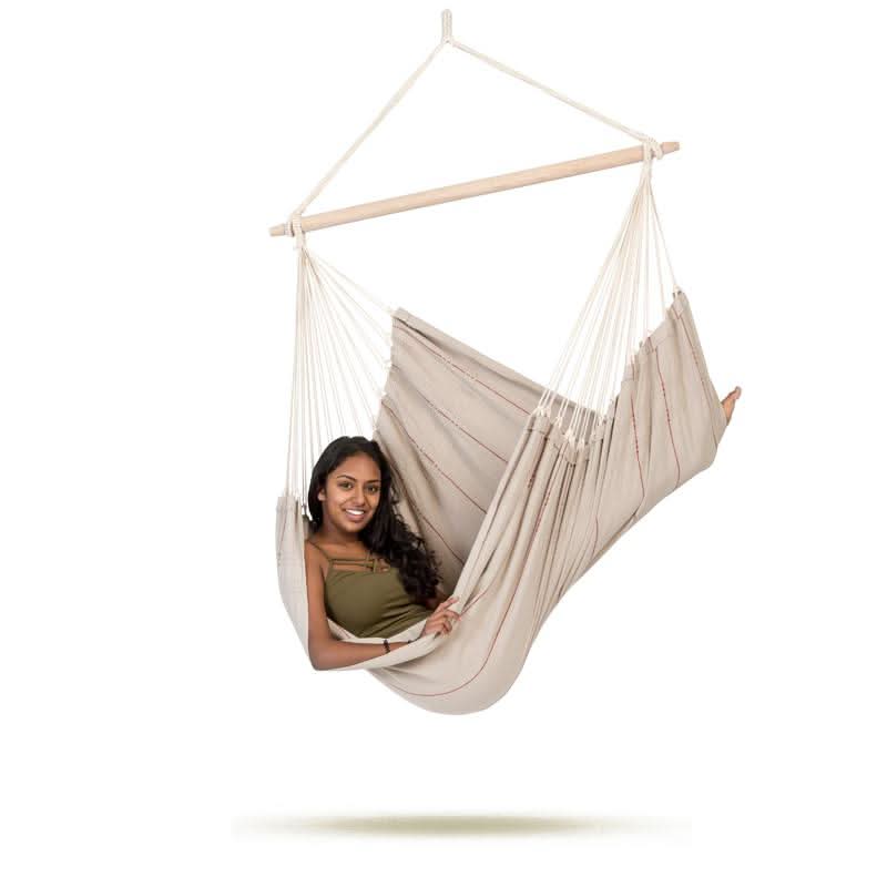 Woman sitting in a beige hammock chair on a white background