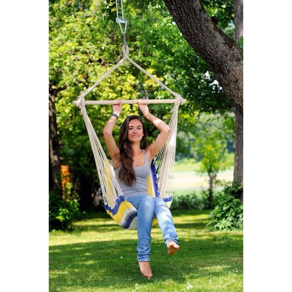 A woman is sitting in a colourful hammock swing outdoors.