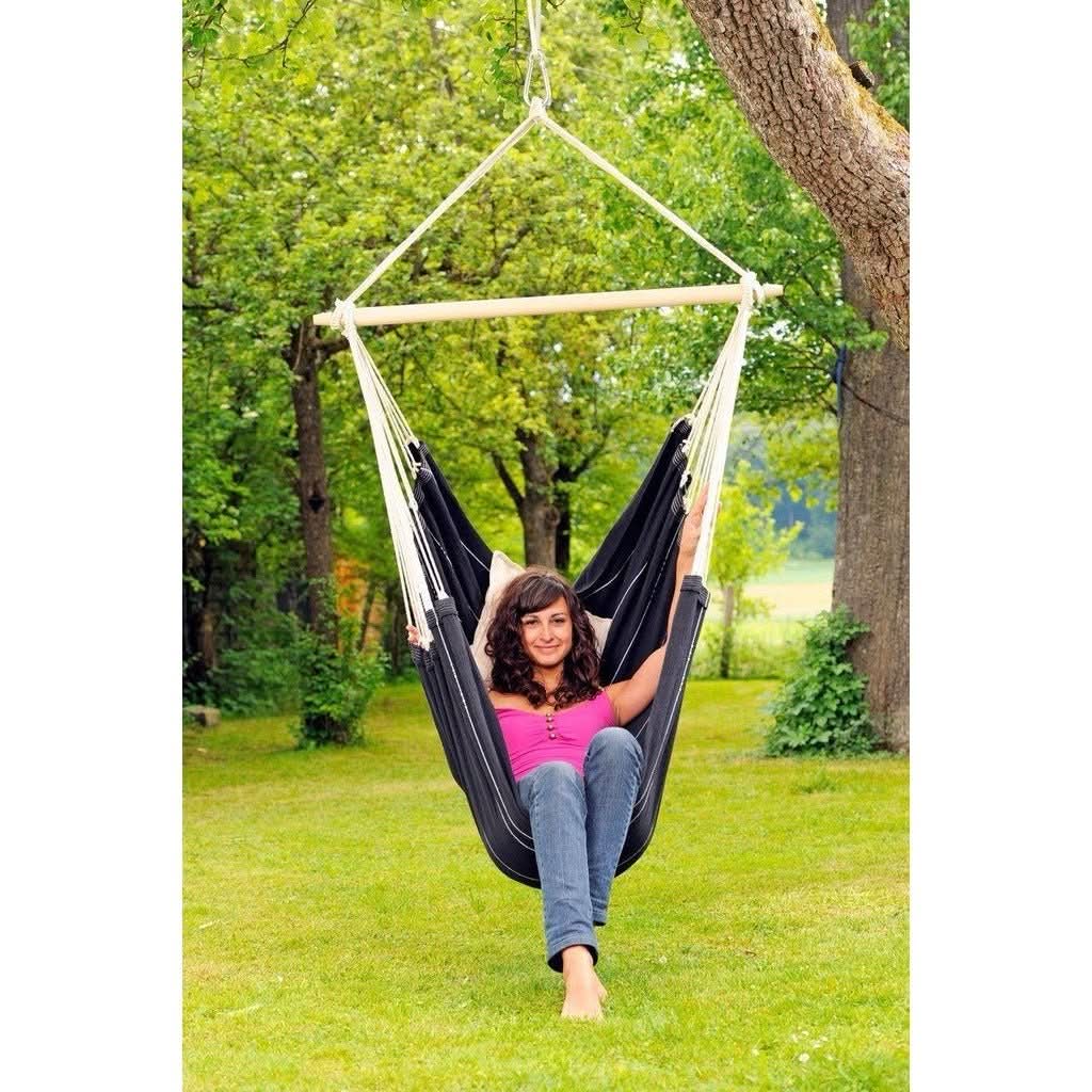 A woman sitting in a black hammock swing in a garden setting
