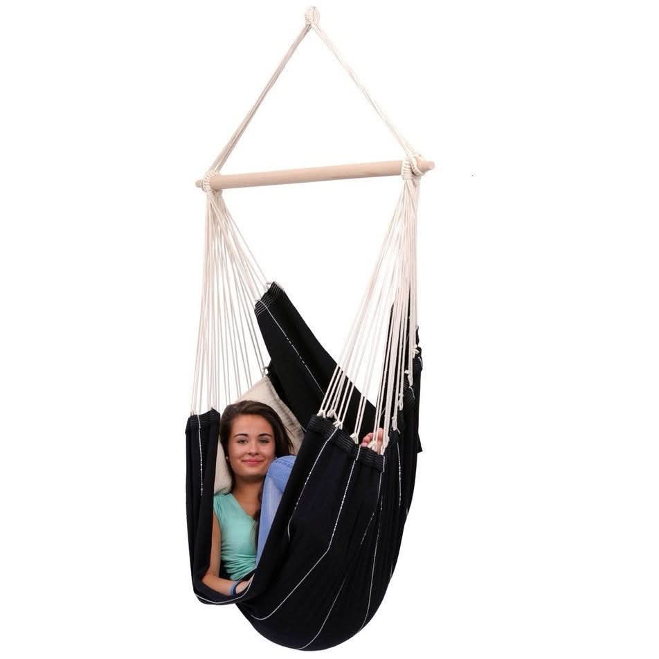 Person sitting in a black hammock chair with white straps on a white background