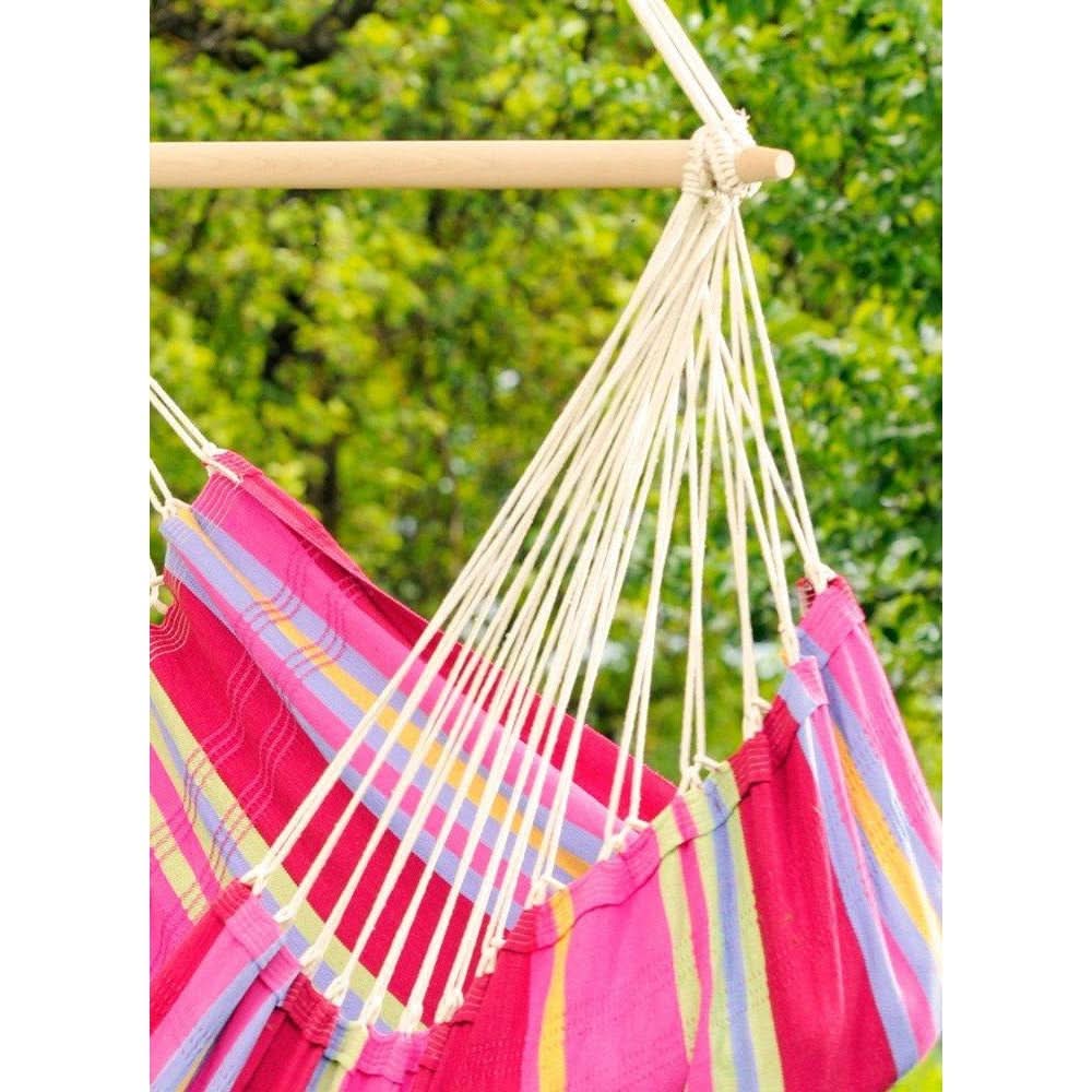 Colourful hammock with pink and multicoloured pattern against a green outdoor background