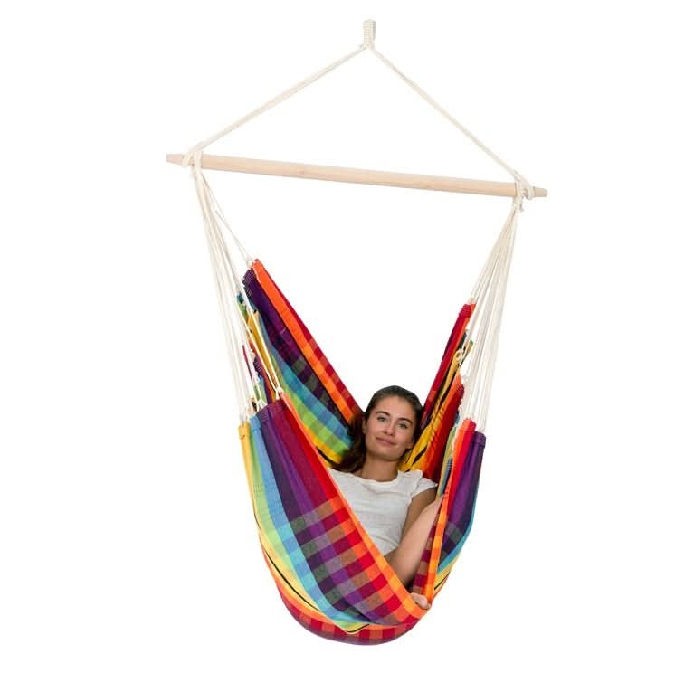 Person sitting in a colourful striped hammock chair on a white background