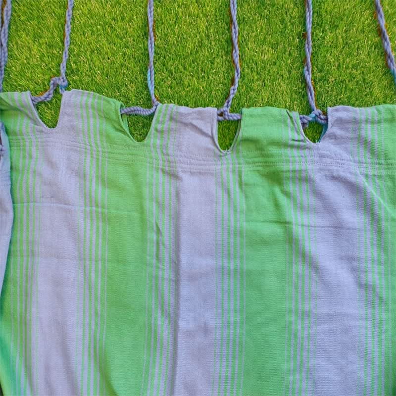 Green and white striped fabric hanging on a line against a grassy background