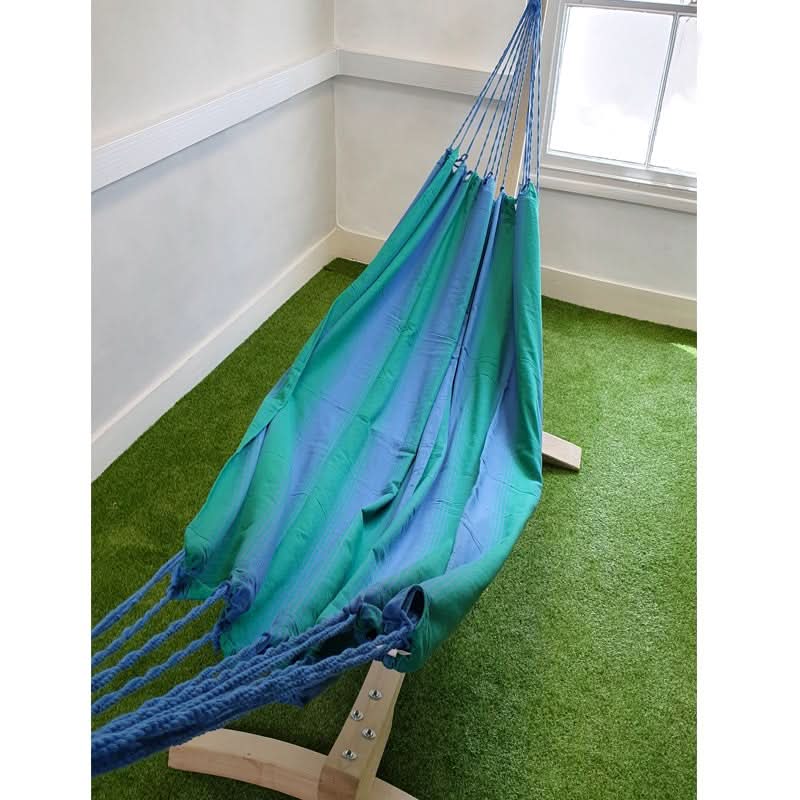 Blue and green hammock on a stand in a room with green flooring.