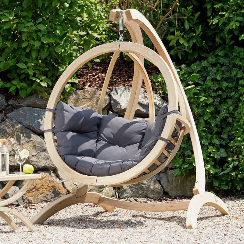 Hanging chair with gray cushion in a garden setting