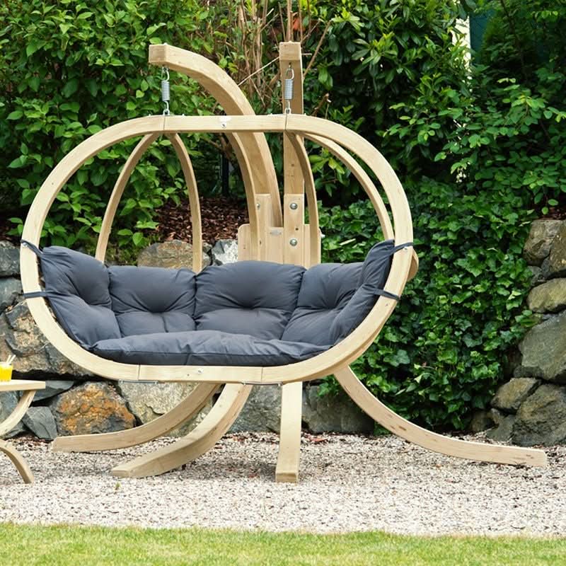 Wooden hanging chair with dark cushions in a garden setting