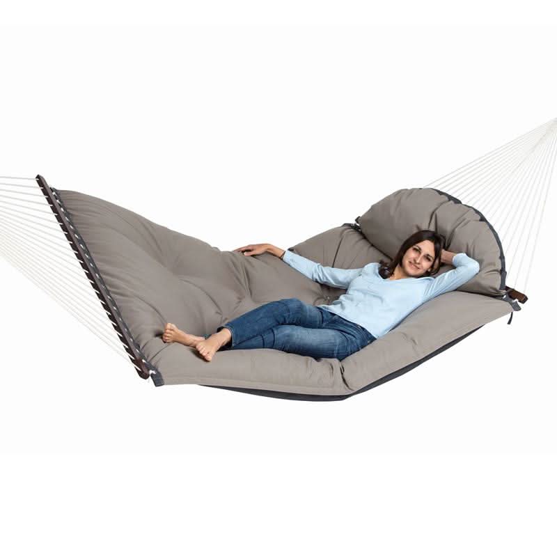 Person relaxing in a large grey hammock on a white background