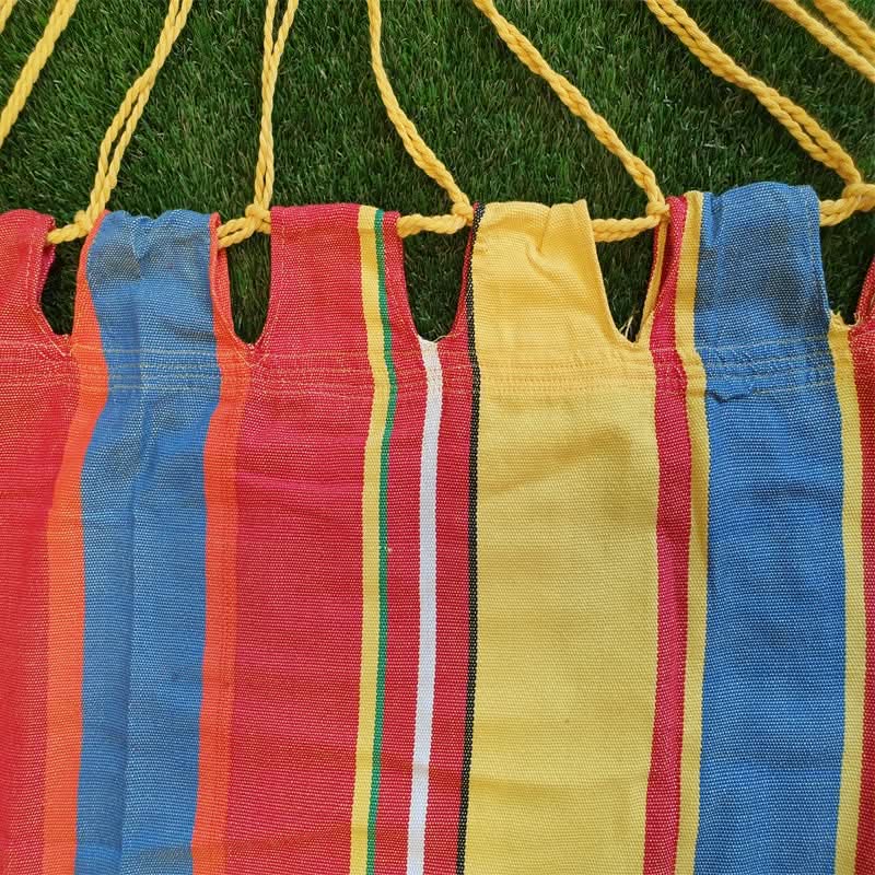 Colourful striped hammock hanging on a green grass background