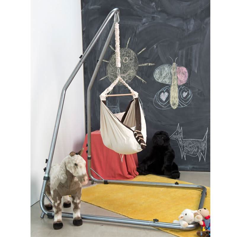 Hanging chair with a goat standing next to it against a chalkboard wall with drawings.