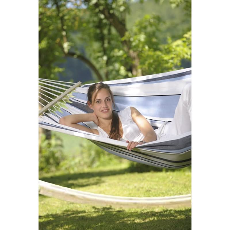 Woman relaxing in a striped hammock with a natural outdoor background