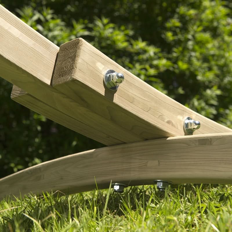Wooden seesaw on grass with blurred greenery in the background