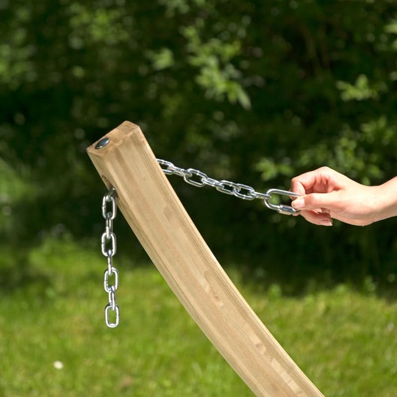 Wooden post with chain and hand holding it against a green outdoor background