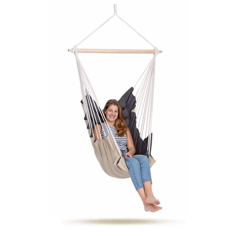 Person sitting in a beige hammock chair on a white background