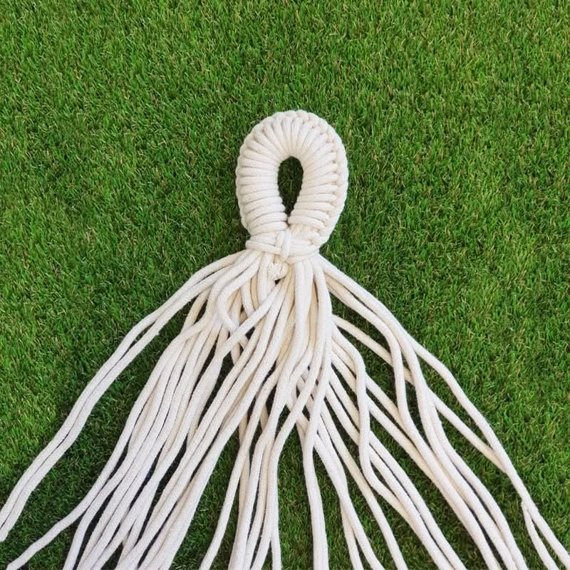 White macrame plant hanger on a green grass background