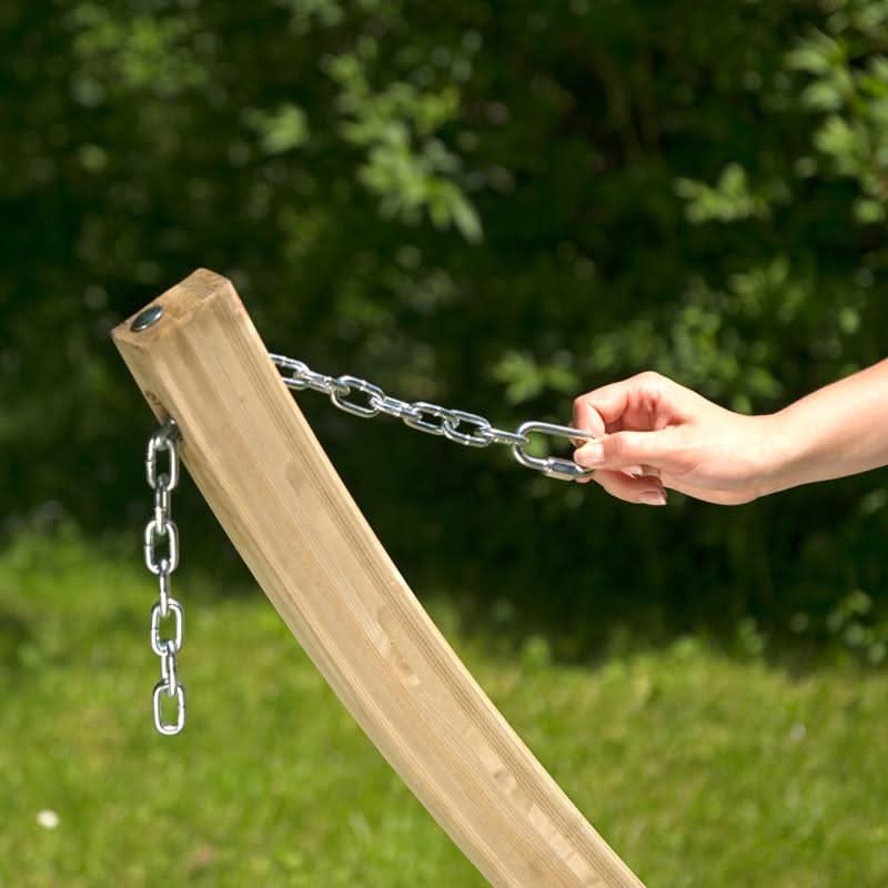 Hand holding a chain attached to a wooden post with a blurred green background