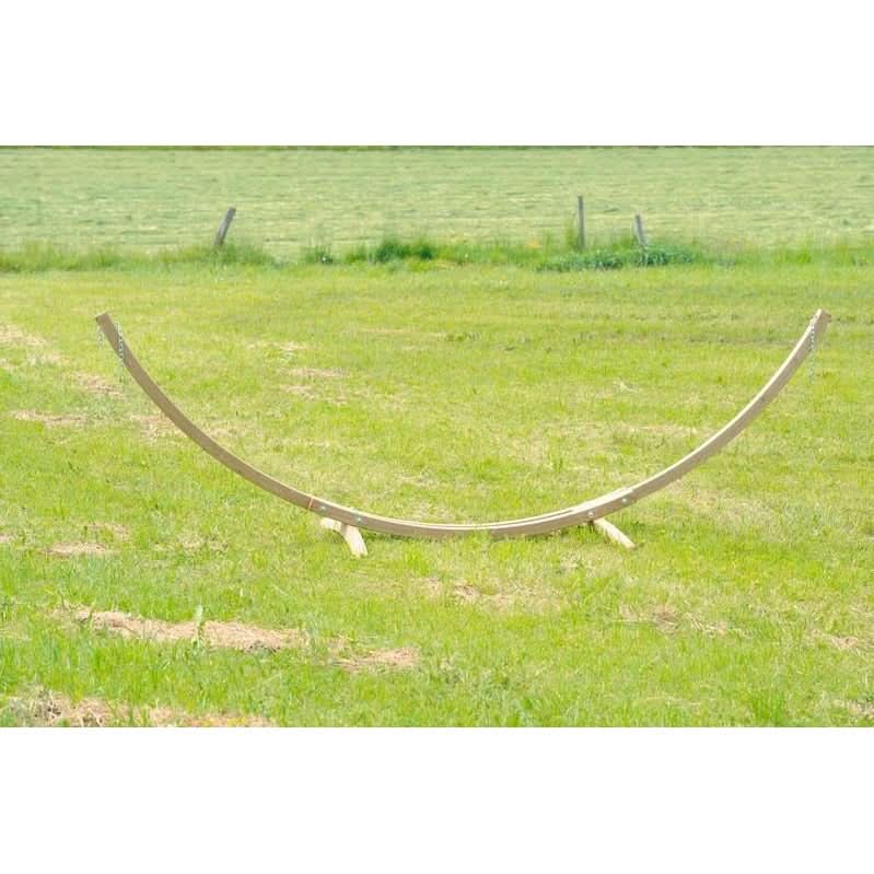 Wooden arch in a grassy field with a fence in the background
