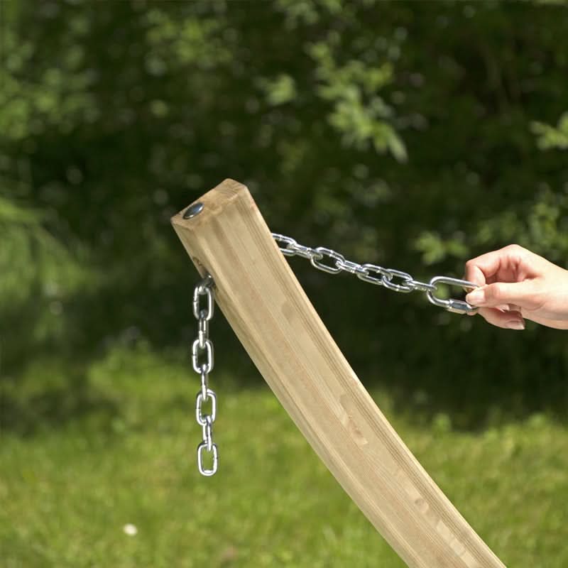Wooden swing set with a chain, held by a hand against a green outdoor background