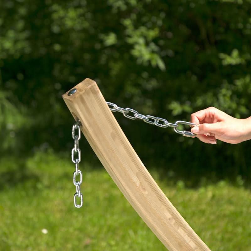 Wooden post with chain attached, held by a hand against a blurred green outdoor background