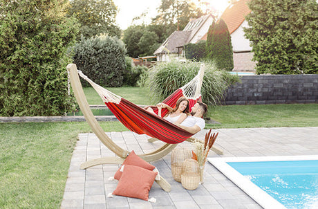 A man and Woman in a red hammock by a pool.