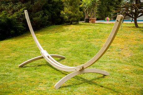 Wooden hammock stand on a grassy lawn with trees and a pool in the background