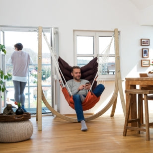 Man sitting in a hammock chair in a modern living room.