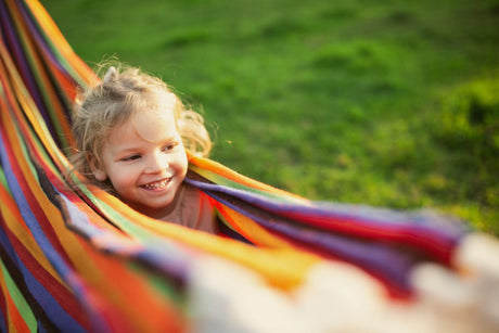 Child in a colourful hammock on a grassy background