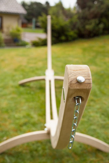 Wooden swing set with a chain in a grassy outdoor setting 