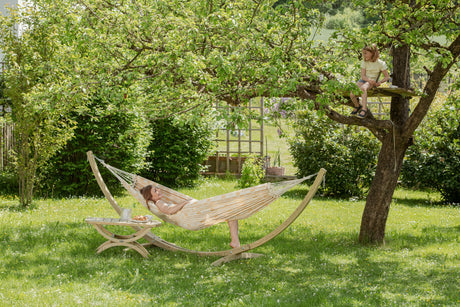 Person relaxing in a hammock under a tree in a garden
