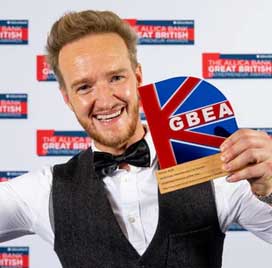 Man in formal attire holding a British flag-themed product with 'GBEA' branding.