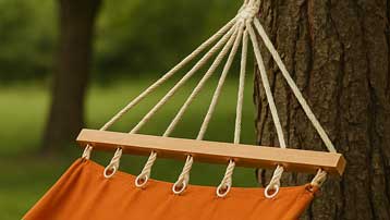 Orange hammock hanging between two trees with a blurred green background