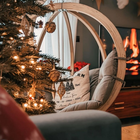 Cosy living room with a decorated Christmas tree, hanging chair, and fireplace.