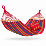 A red fabric hammock with blue, green, and yellow stripes, featuring light wood spreader bars and a matching red striped pillow, shown against a plain white background.