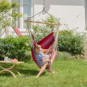 A child and a woman sat in a pink and red hanging chair 