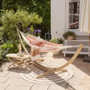 Outdoor setting with a hammock, and tavolino table, and on a patio.